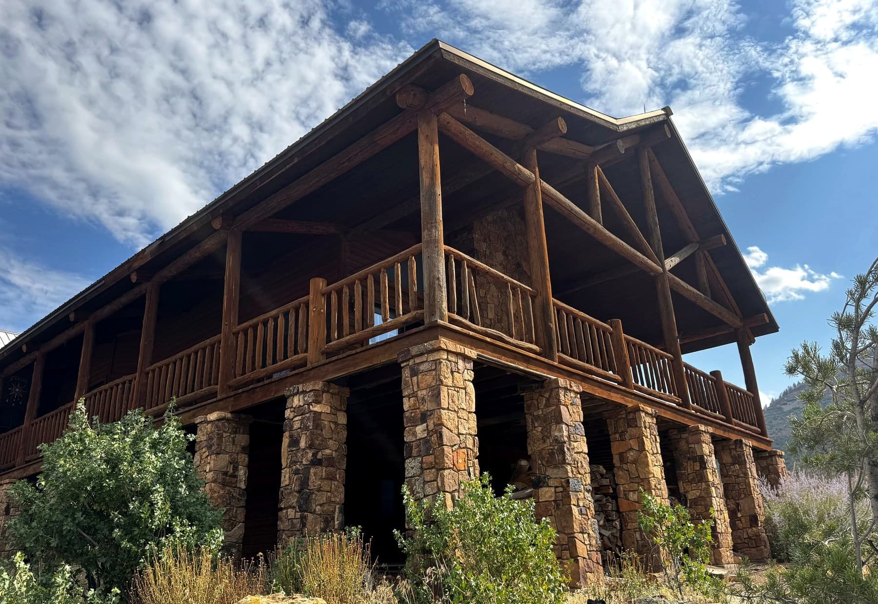 Log lodge wraparound deck and stone pillars